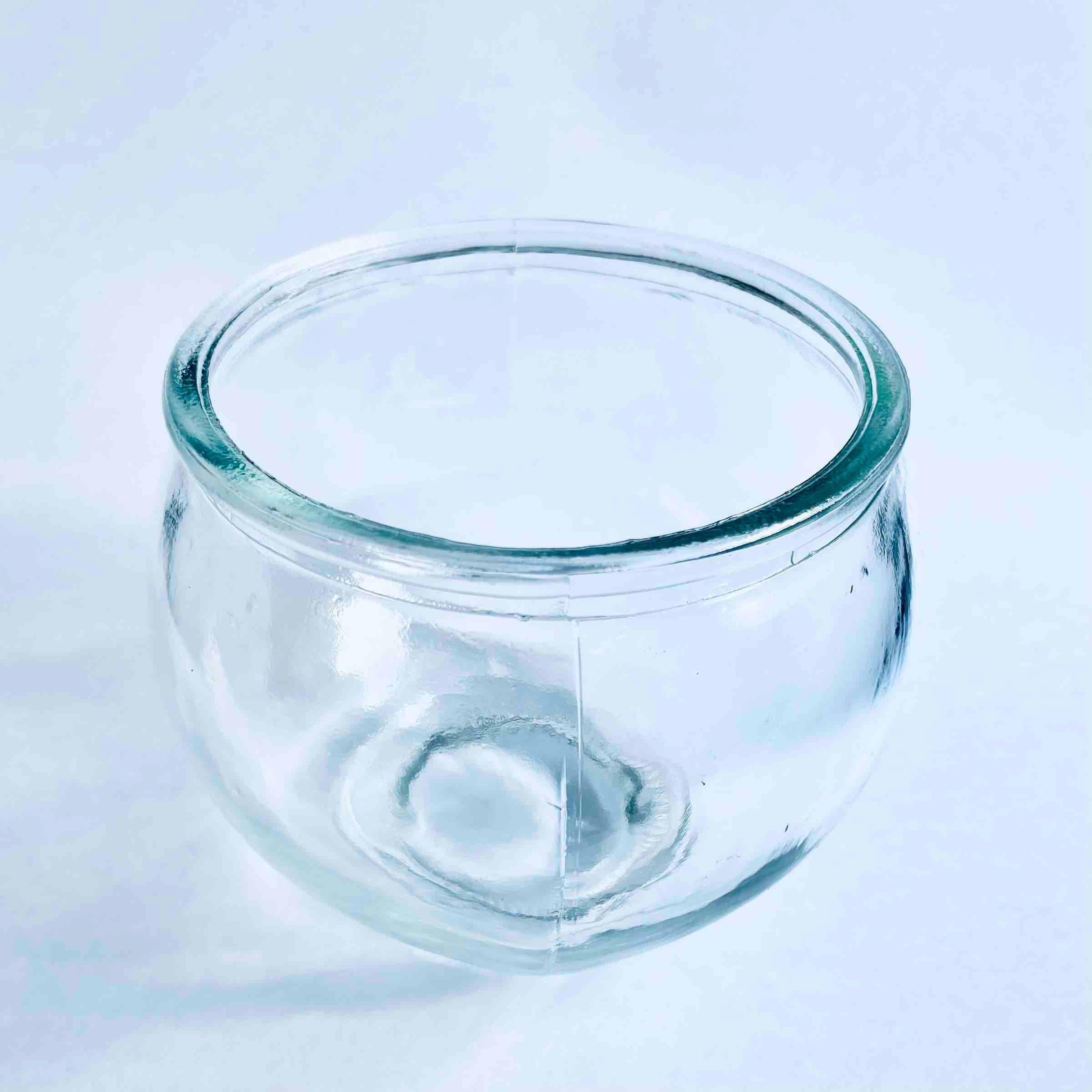Transparent round glass candle holder with thick rim on white surface